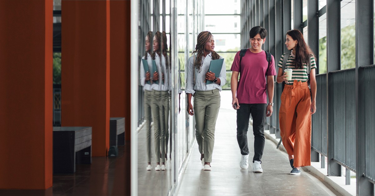 Photo of three people walking down a hallway on campus