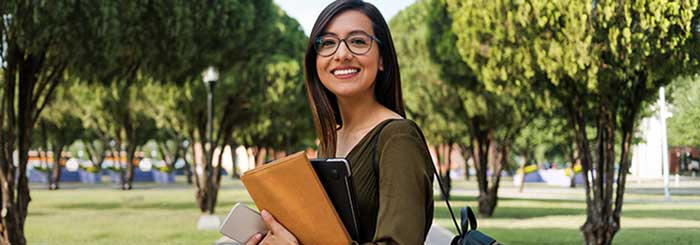 Woman carrying books and computer on the way to class