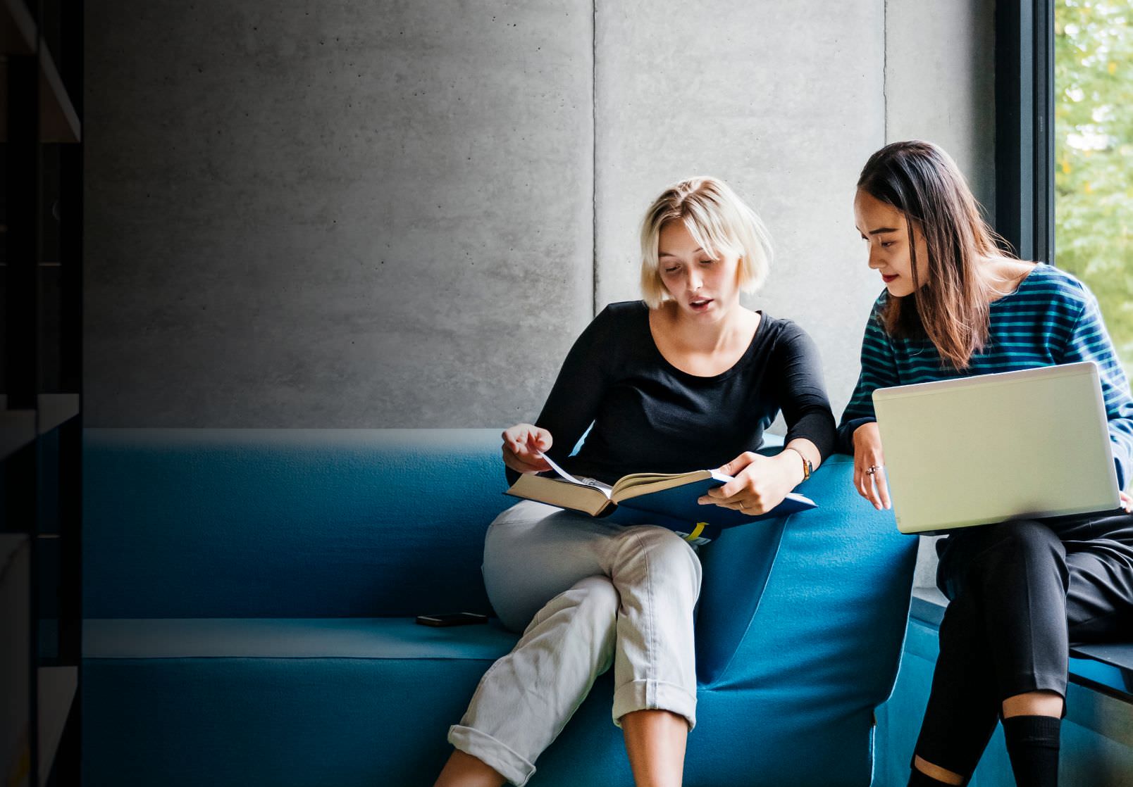 two women sitting around a couch studying