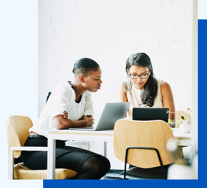 Photo of two people working together at their laptops