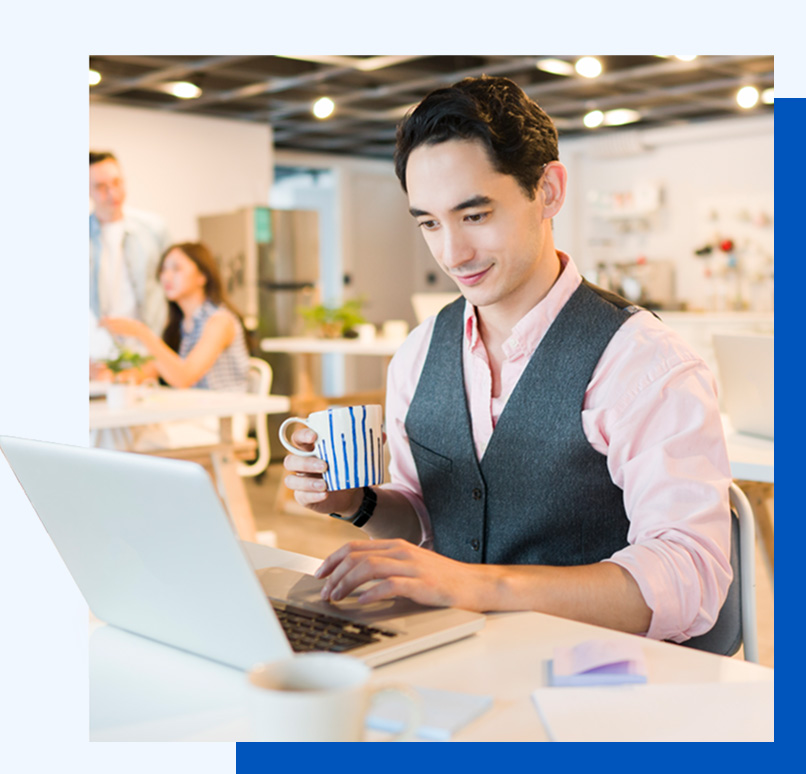 Photo of a man working at a laptop in an open office setting