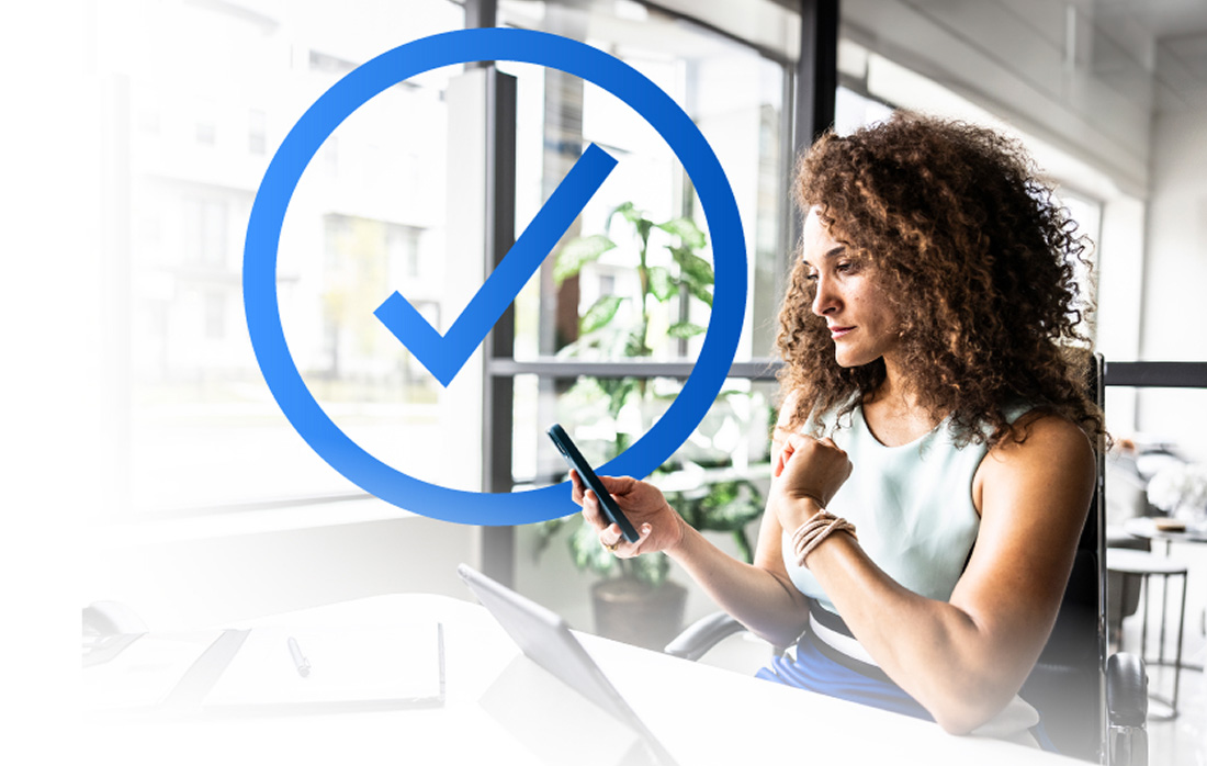 Photo of a woman looking at her phone while sitting at her desk