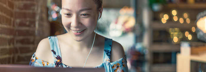 Student using laptop wearing earphones.