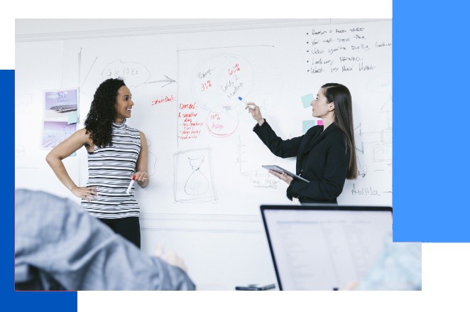 Two people in front of a white board