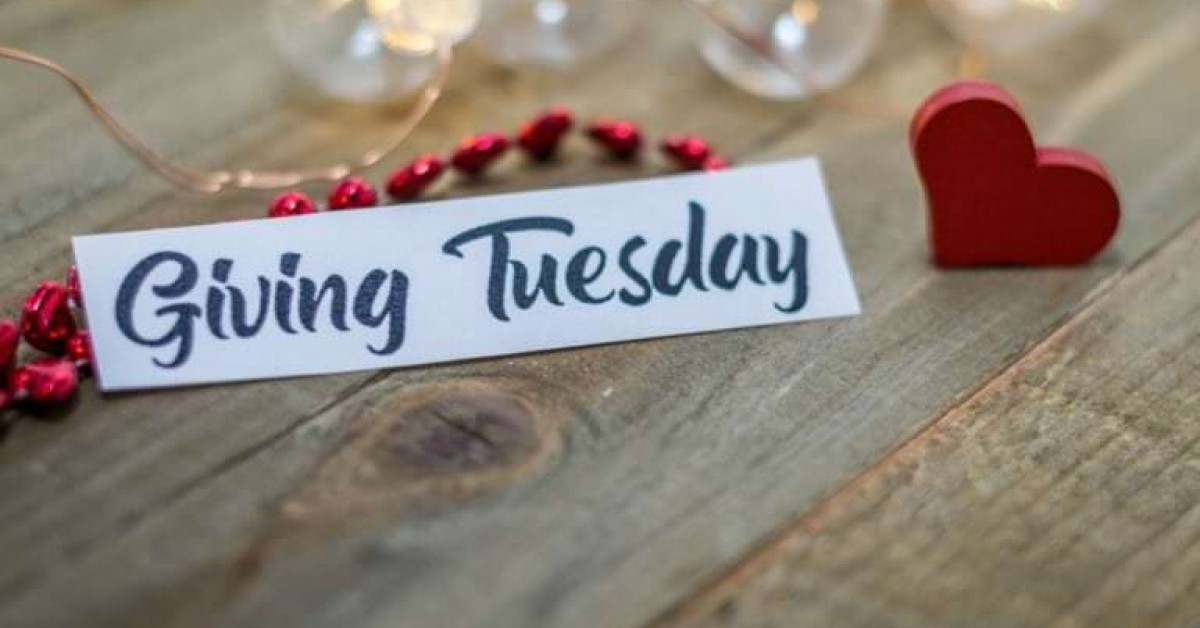 Close up photo of a sign that says Giving Tuesday on a table next to a heart
