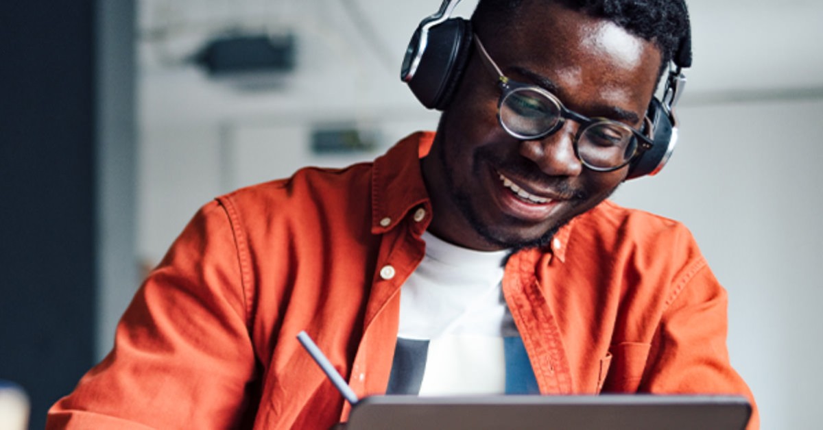 Photo of a student wearing headphones and working at a tablet