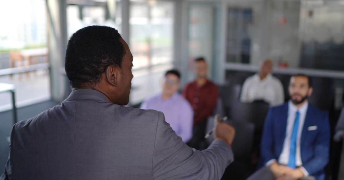 A man giving a presentation in front of a room of colleagues