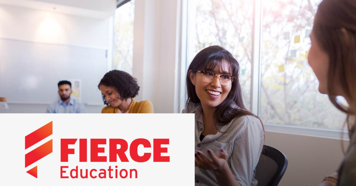 Image of a student talking to her teacher in a classroom with two more students. On the lower left corner of the graphic is placed the Fierce Education logo. 