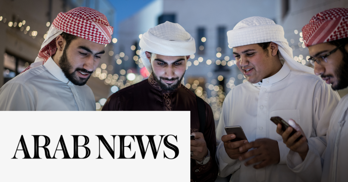 Image of four Arab men  checking their mobile phones with the Arab News logo on the lower left corner of the graphic. 