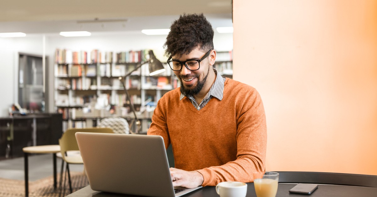 Photo of a learner working on a laptop in a library