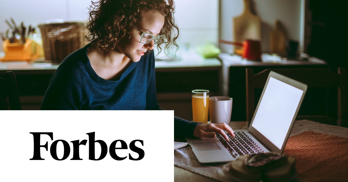 Person with curly hair and glasses working on a laptop in a dimly lit kitchen. "Forbes" text at the bottom left.