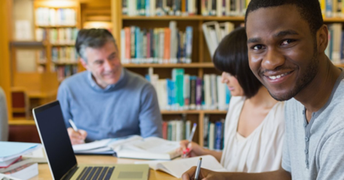 Student in library with classmates and instructor.