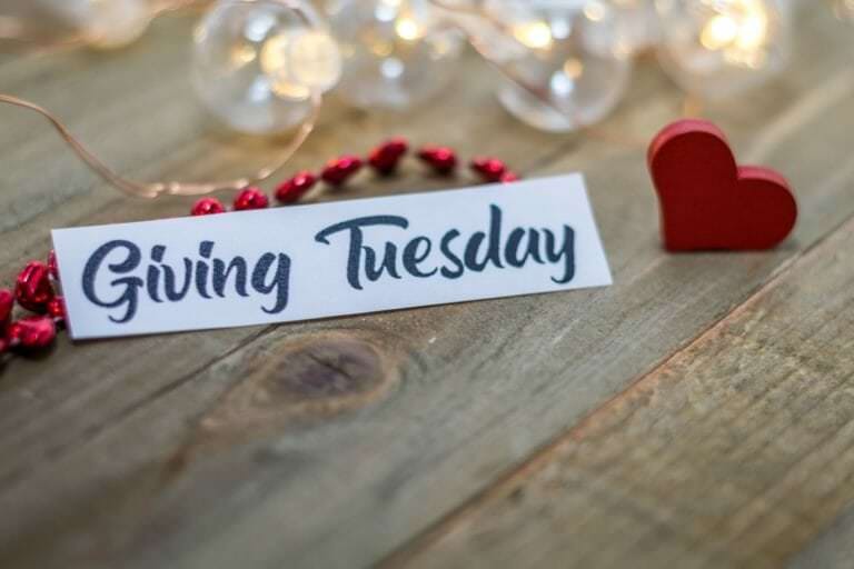 Close up photo of a sign that says Giving Tuesday on a table next to a heart