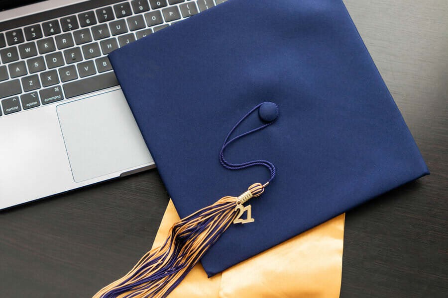 Photo of a graduation cap on top of a laptop