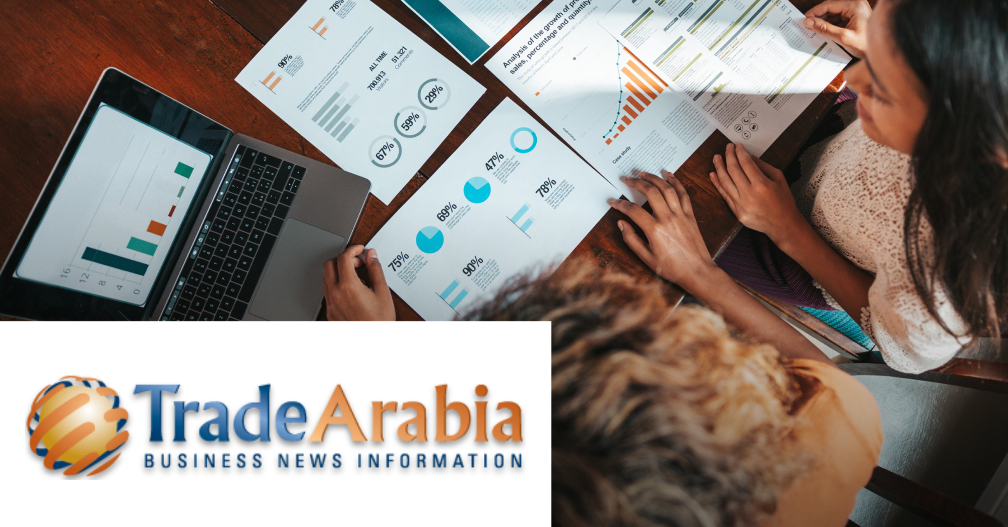 Image of two women working with some documents and a laptop on a table. On the lower left corner is placed the Trade Arabia logo.