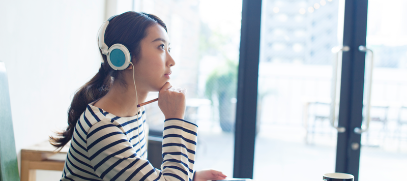 Photo of a woman wearing headphones looking out a window